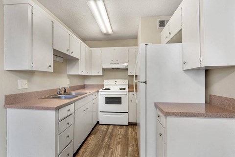 A kitchen with white cabinets and appliances.